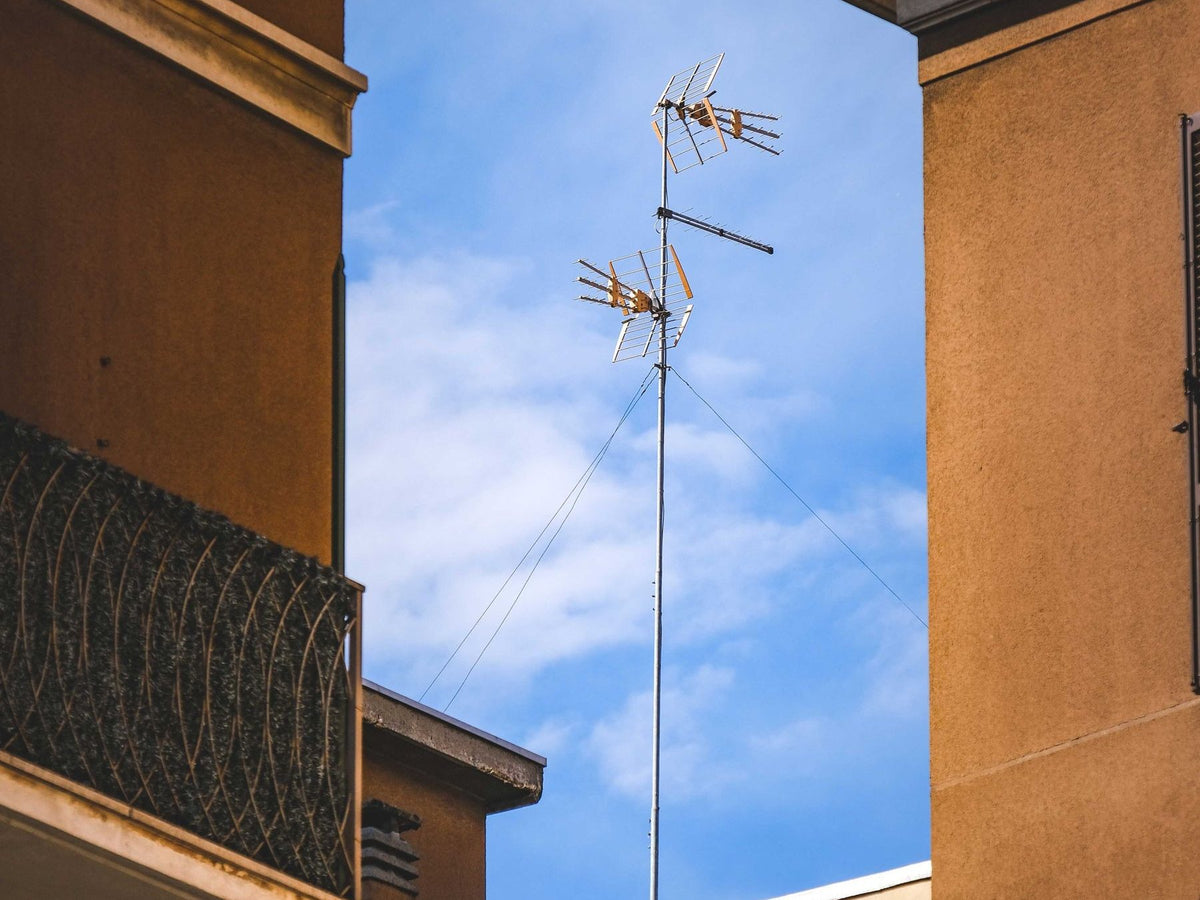 Rooftop television and radio antennas against a blue sky