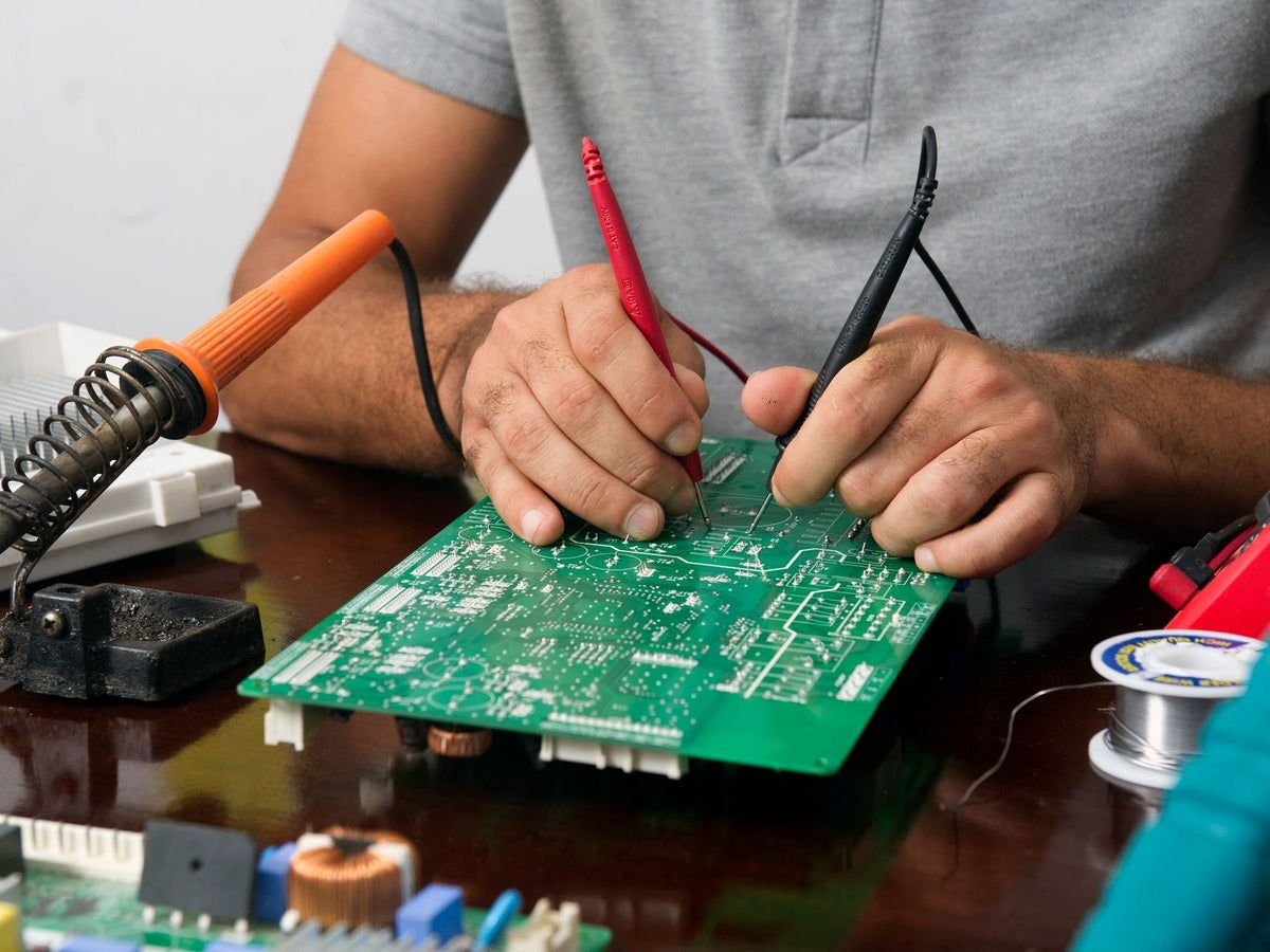 Technician soldering a circuit board at a workbench