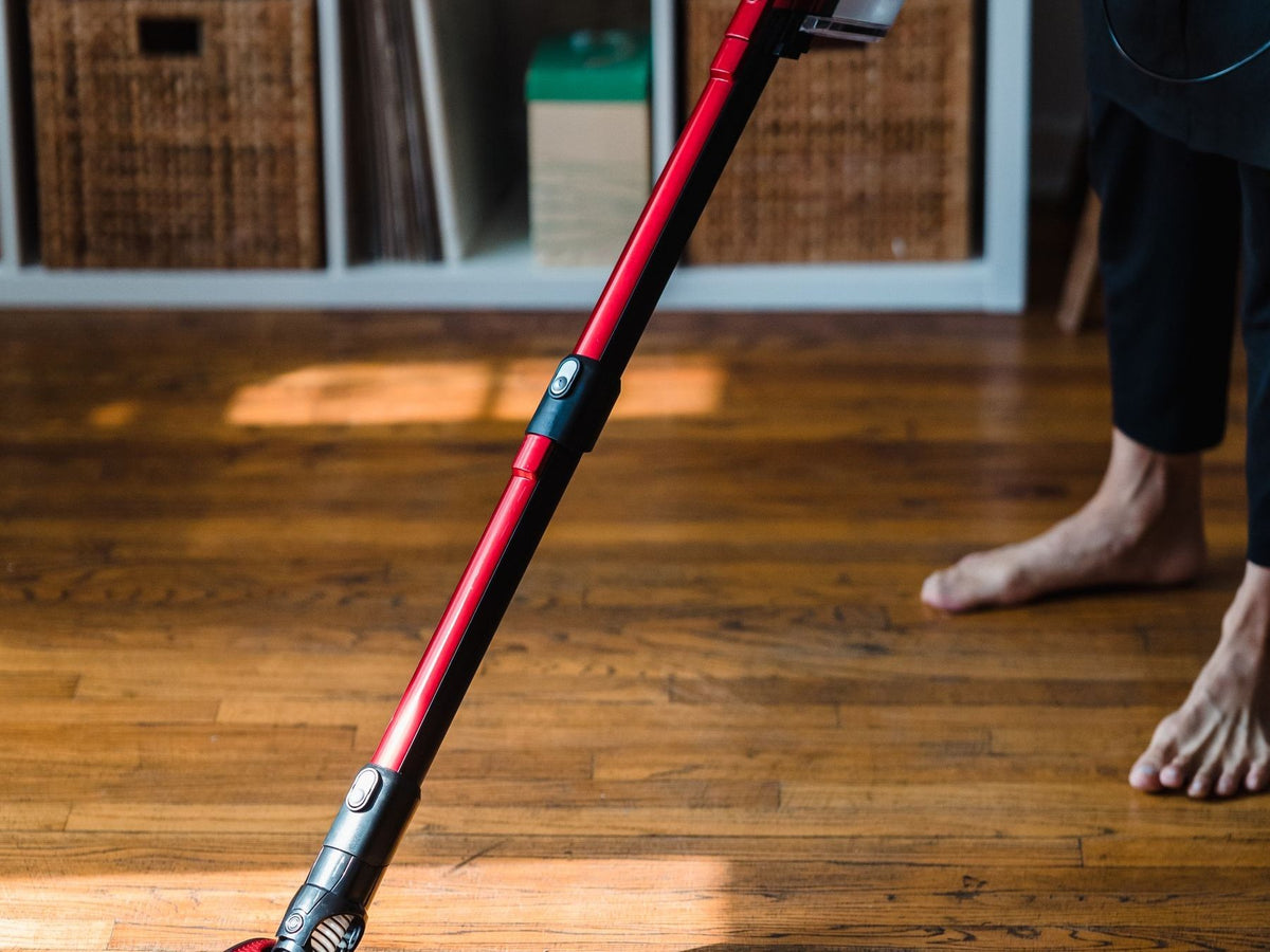 Cordless stick vacuum cleaner being used on a wooden floor